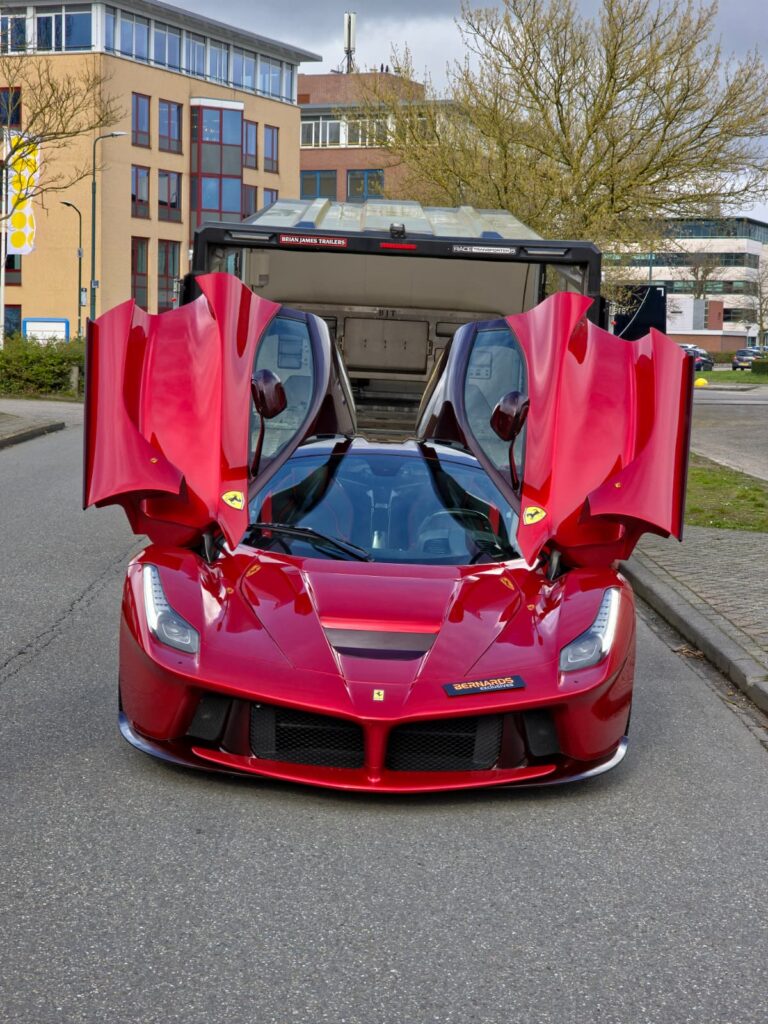 Rode Ferrari LaFerrari met geopende vleugeldeuren voor de gesloten trailer