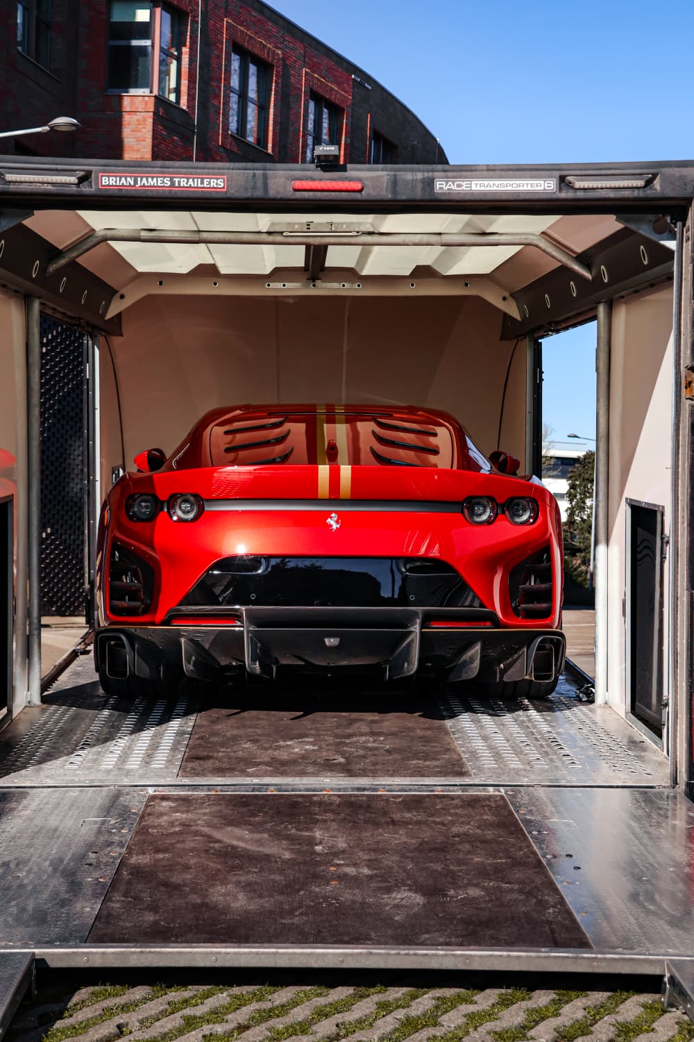 Rode Ferrari met gouden streep achterin de gesloten transporttrailer